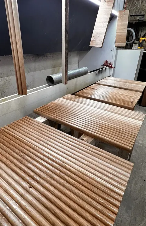 Panneaux de bois cannelés posés sur un établi de l'atelier.